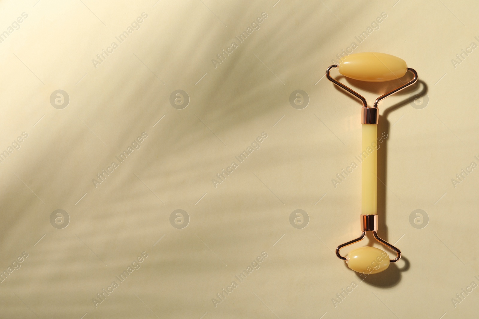 Photo of Natural jade face roller on beige background, top view. Space for text