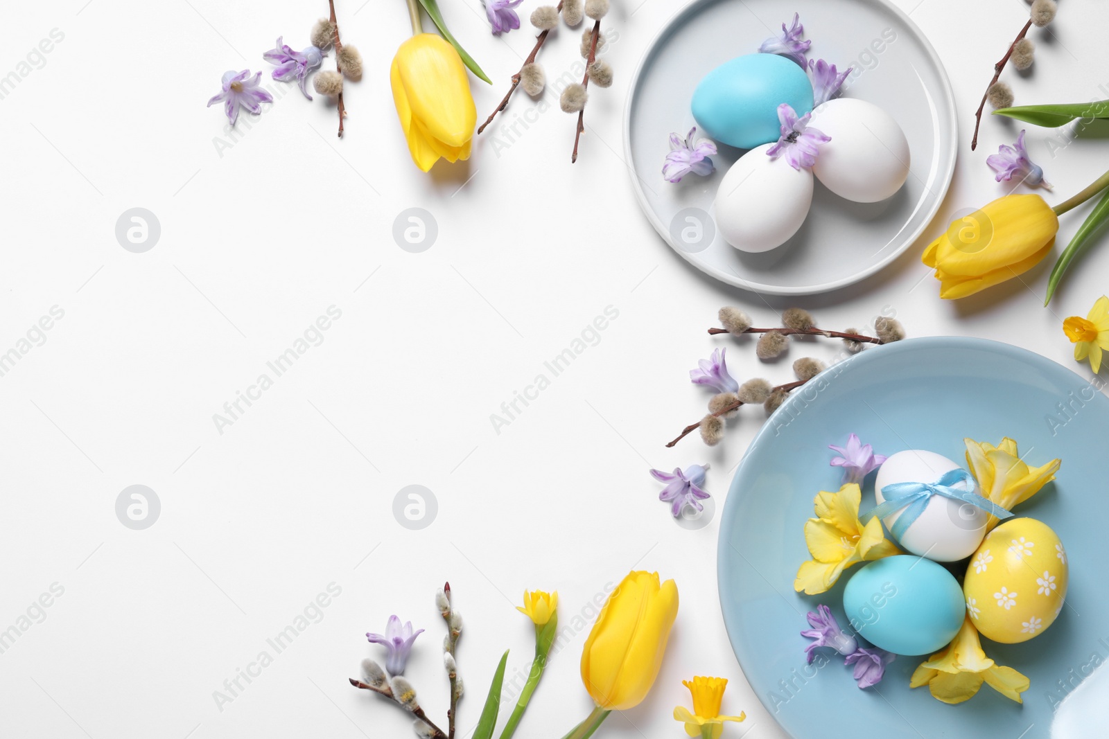 Photo of Festive Easter table setting with painted eggs and floral decor on white background, flat lay. Space for text