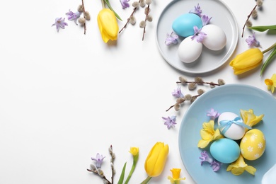 Photo of Festive Easter table setting with painted eggs and floral decor on white background, flat lay. Space for text