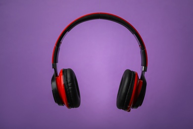 Photo of Wireless headphones with earmuffs on color background