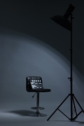 Photo of Casting call. Chair, clapperboard and lamp in modern studio