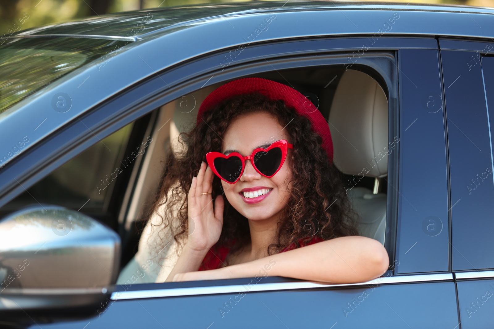 Photo of Young beautiful African-American woman wearing heart shaped glasses in car