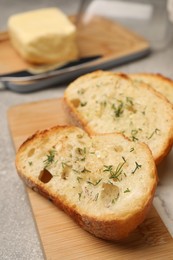 Photo of Tasty baguette with garlic and dill on light grey table, closeup