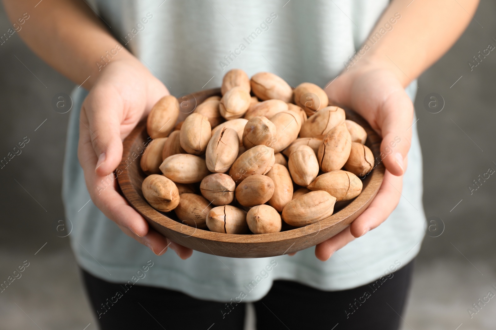 Photo of Woman holding bowl with pecan nuts in hands, closeup