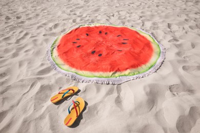 Flip flops and watermelon beach towel with tassels on sand