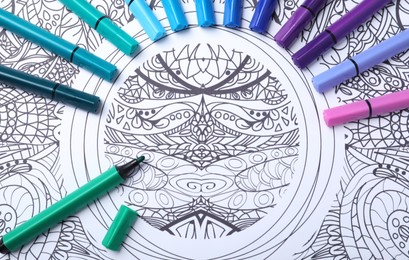 Photo of Felt tip pens on antistress coloring page, top view