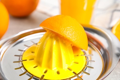 Photo of Cut fresh ripe orange and squeezer on table, closeup