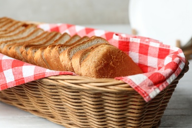 Photo of Slices of bread in basket on white table, closeup