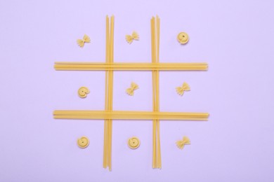 Photo of Tic tac toe game made with different types of pasta on lilac background, top view