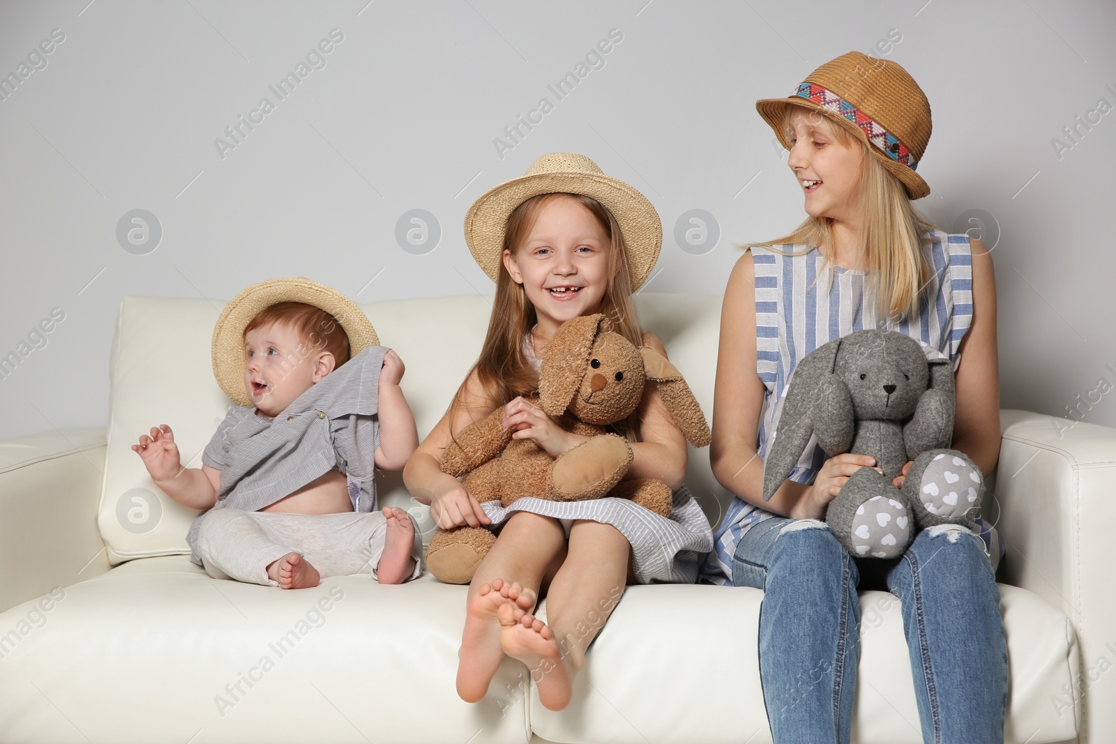 Photo of Happy children wearing hats on sofa at home