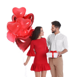 Photo of Happy young couple with gift box and heart shaped balloons isolated on white. Valentine's day celebration