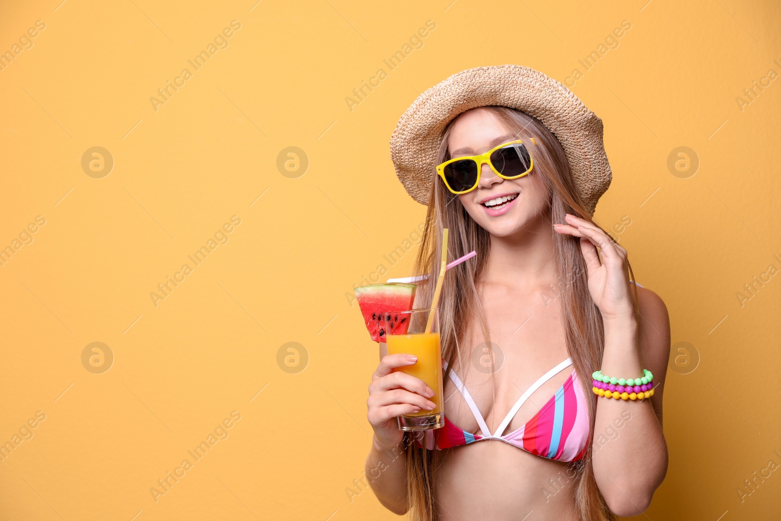 Photo of Beautiful young woman in bikini and hat with cocktail on color background