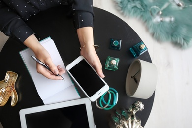 Female blogger with smartphone and notebook at table, closeup