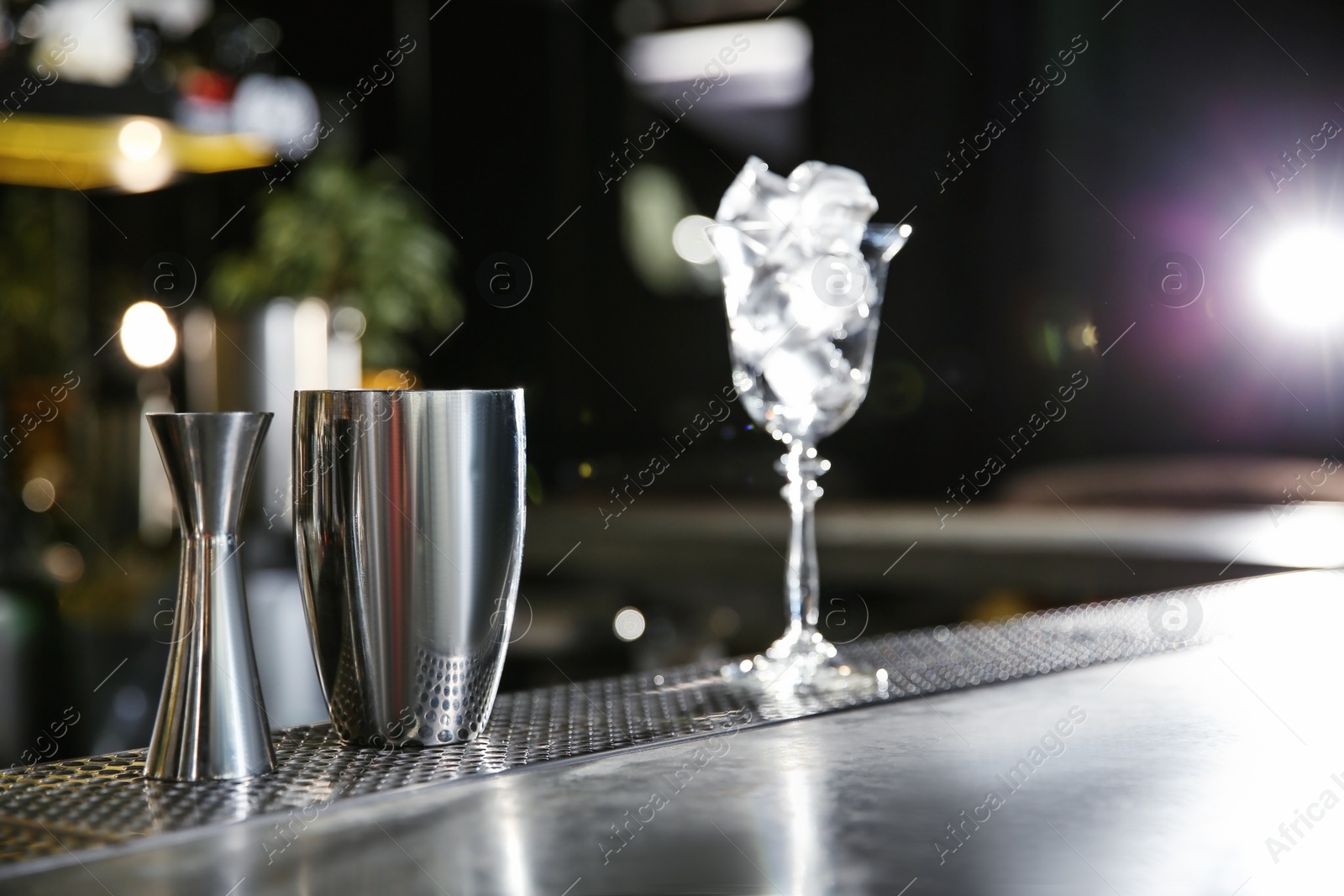 Photo of Shaker and jigger on bar counter, space for text. Making martini cocktail