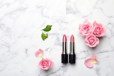 Flat lay composition with lipsticks, roses and space for text on marble background