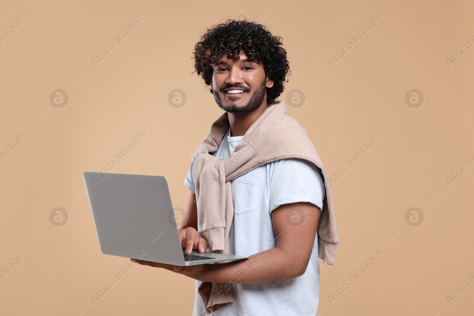 Photo of Smiling man with laptop on beige background