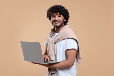 Smiling man with laptop on beige background
