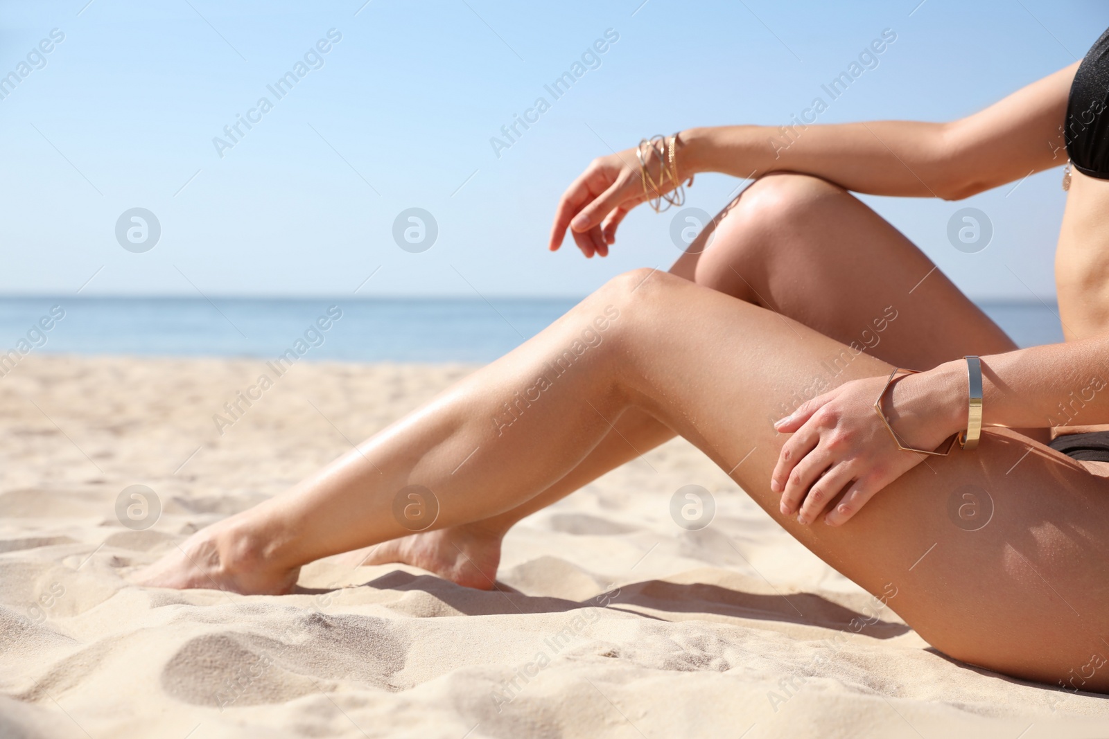 Photo of Young woman with beautiful body on sandy beach, closeup