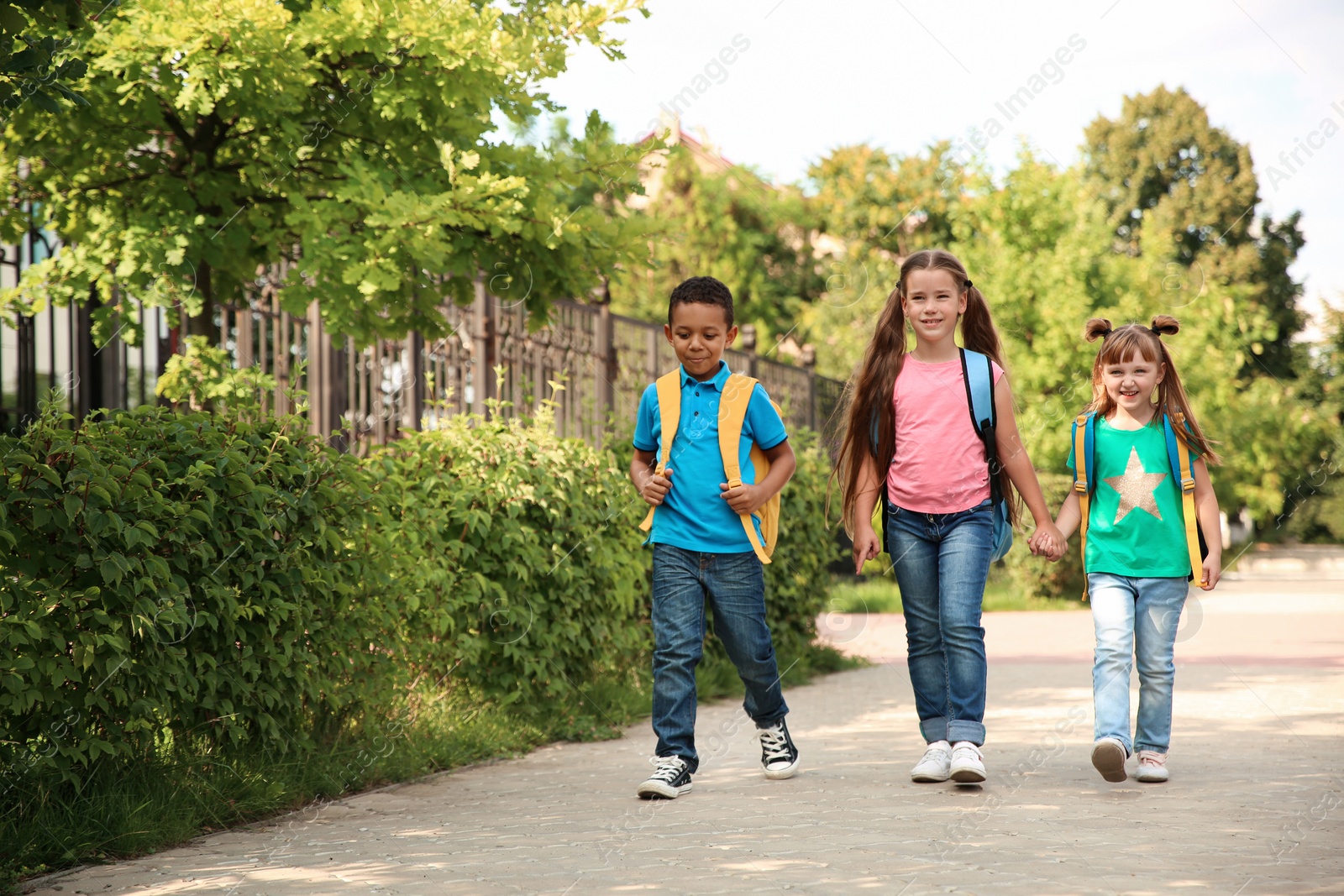 Photo of Cute little children with backpacks going to school