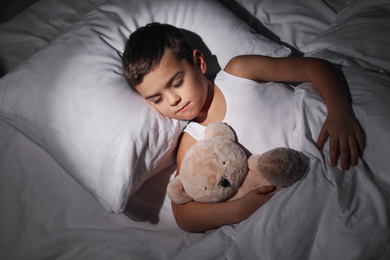 Photo of Little boy sleeping with teddy bear at home. Bedtime