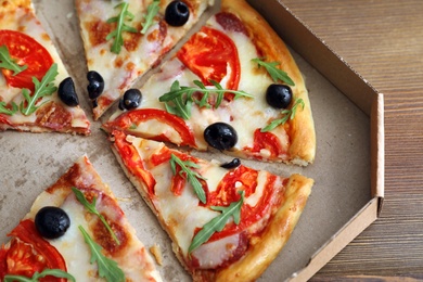 Cardboard box with tasty pizza on table, closeup