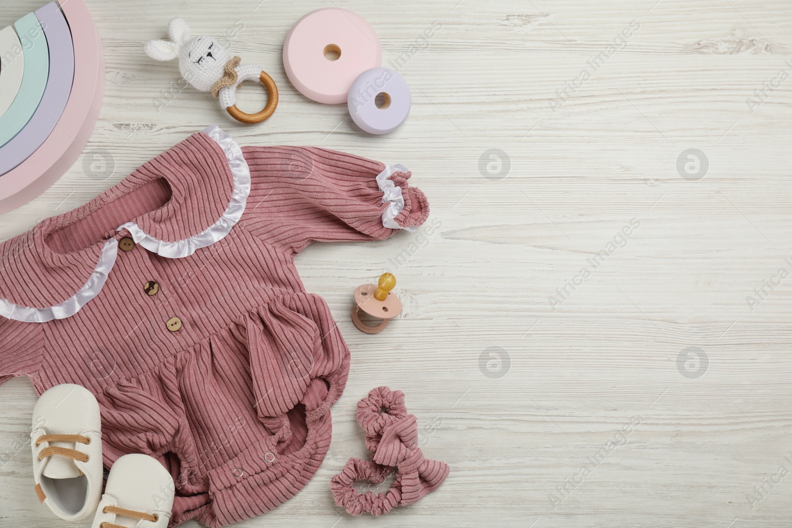 Photo of Flat lay composition with baby clothes and accessories on white wooden table. Space for text