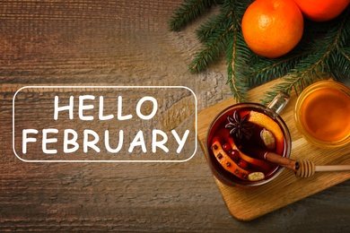 Image of Hello February greeting card. Composition with glass cup of tasty mulled wine on wooden background, flat lay