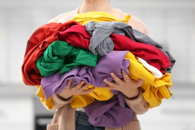 Woman holding pile of dirty laundry indoors, closeup