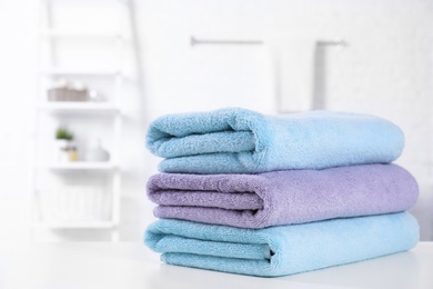 Photo of Stack of fresh towels on table in bathroom. Space for text