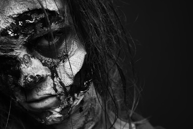 Photo of Scary zombie on dark background, black and white effect. Halloween monster