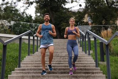 Photo of Healthy lifestyle. Happy couple running down stairs outdoors