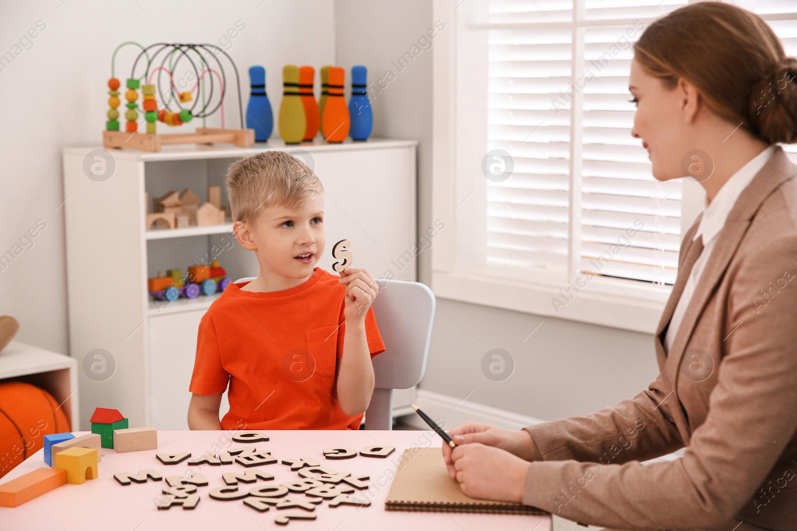 Photo of Speech therapist working with little boy in office