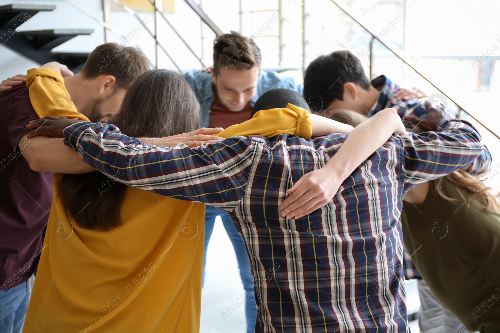 Photo of People standing together in circle indoors. Unity concept