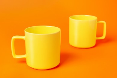 Photo of Two yellow ceramic mugs on orange background