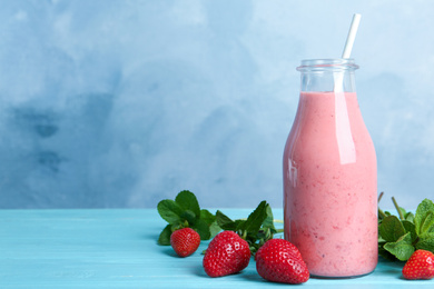 Photo of Tasty strawberry smoothie and mint on light blue wooden table. Space for text