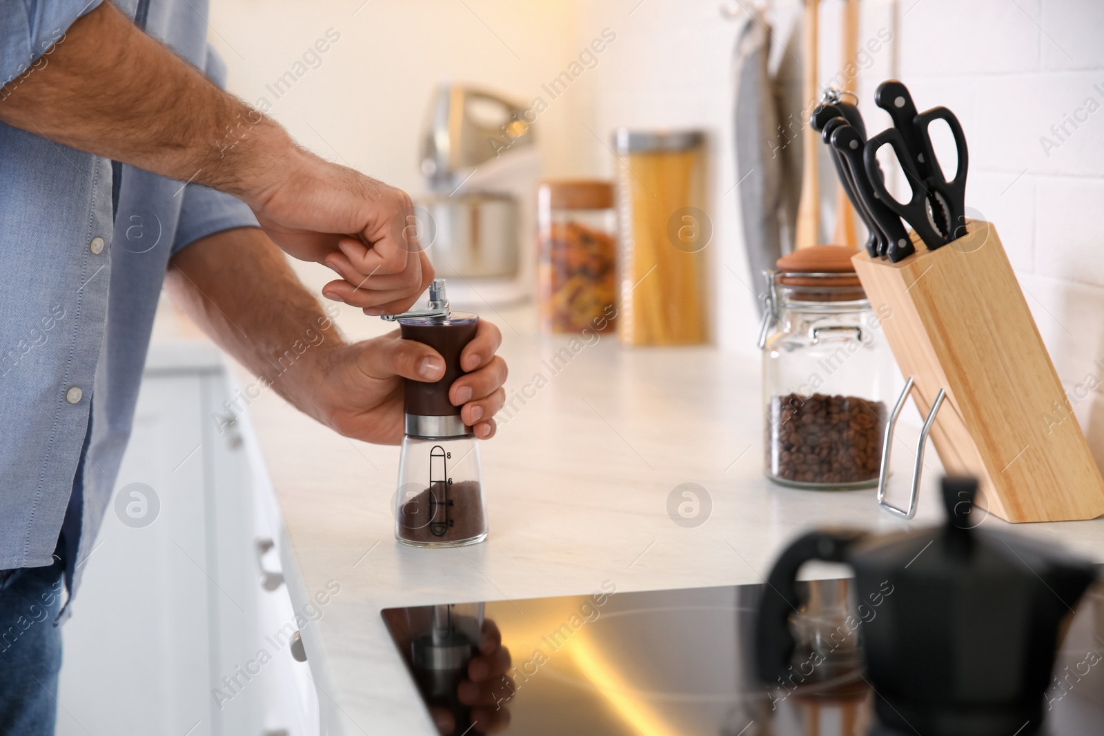 Photo of Man using manual coffee grinder in kitchen, closeup