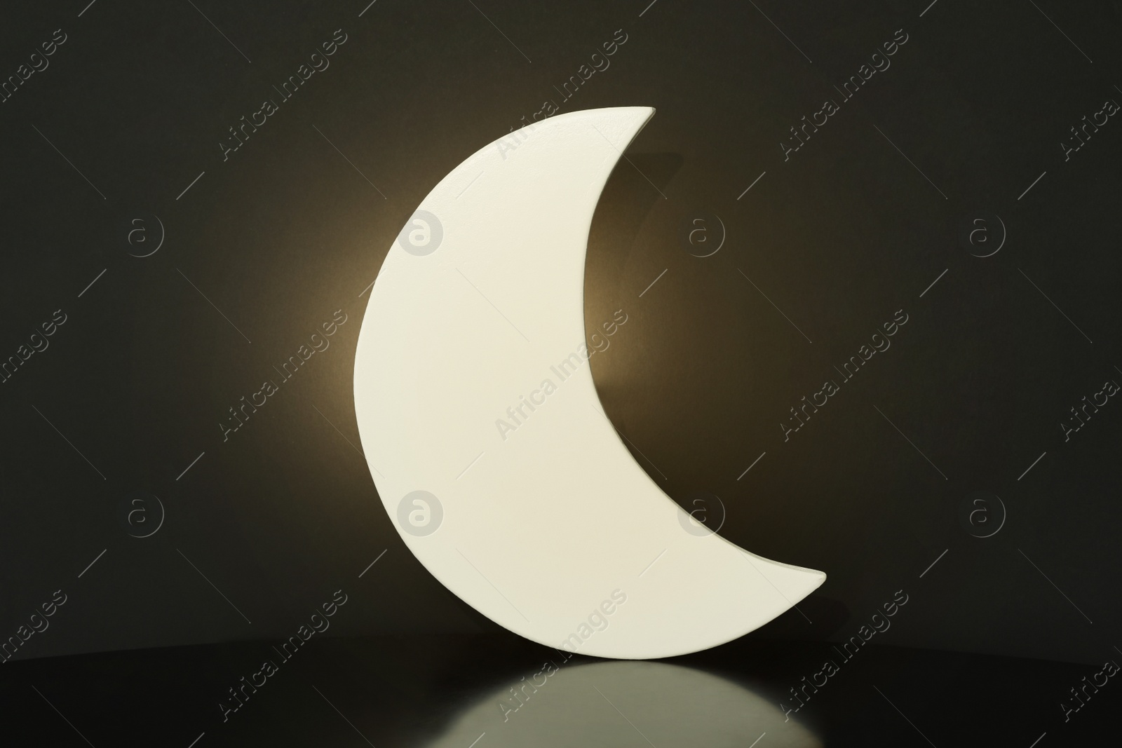 Photo of Crescent shaped glowing night lamp on black background