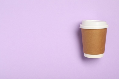 Takeaway paper coffee cup on violet background, top view. Space for text