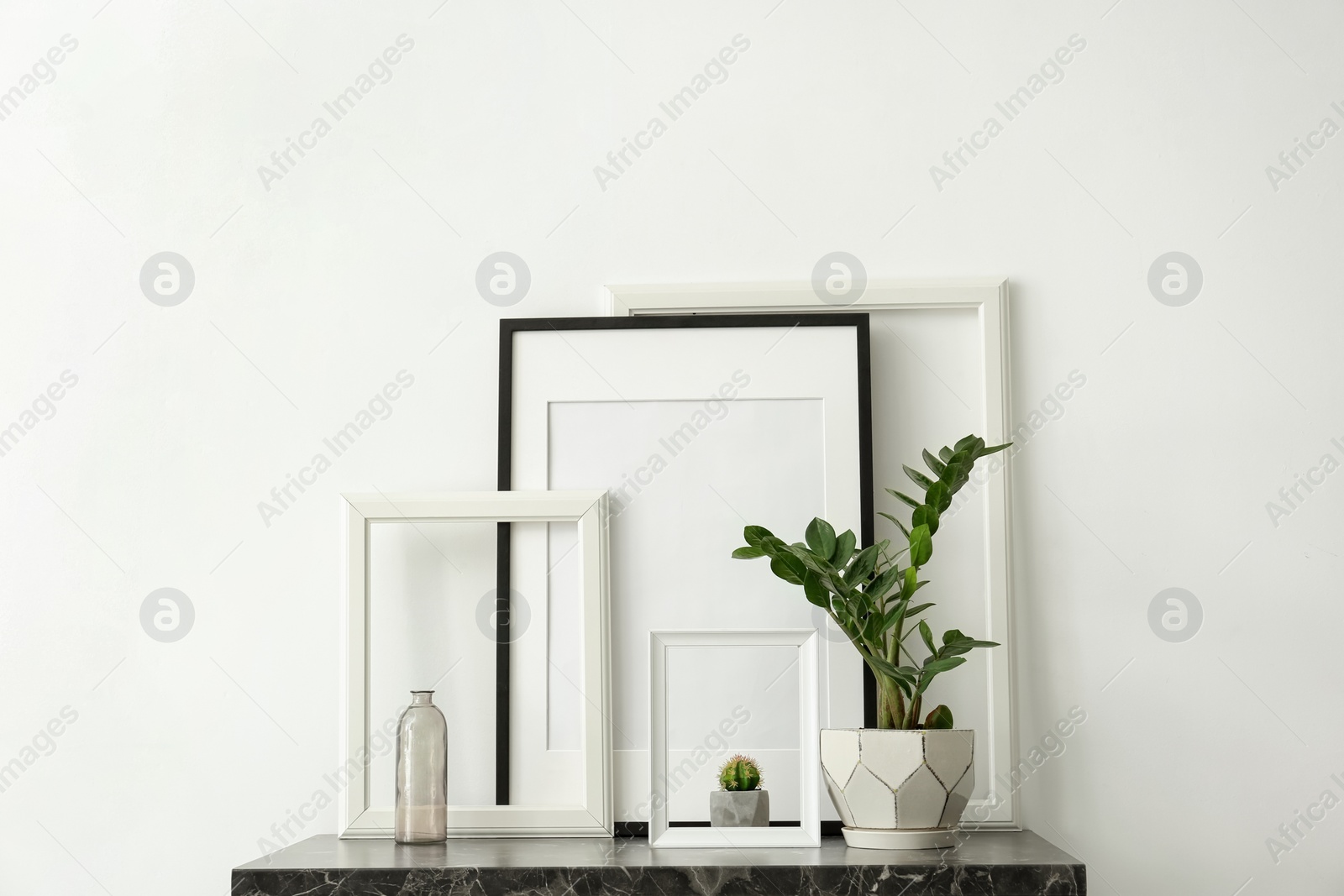 Photo of Mockup of blank frame and houseplant on table