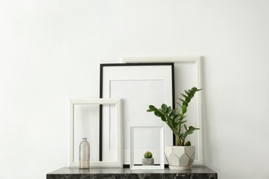 Photo of Mockup of blank frame and houseplant on table