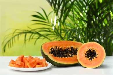 Photo of Fresh juicy cut papayas on white table against blurred background, space for text