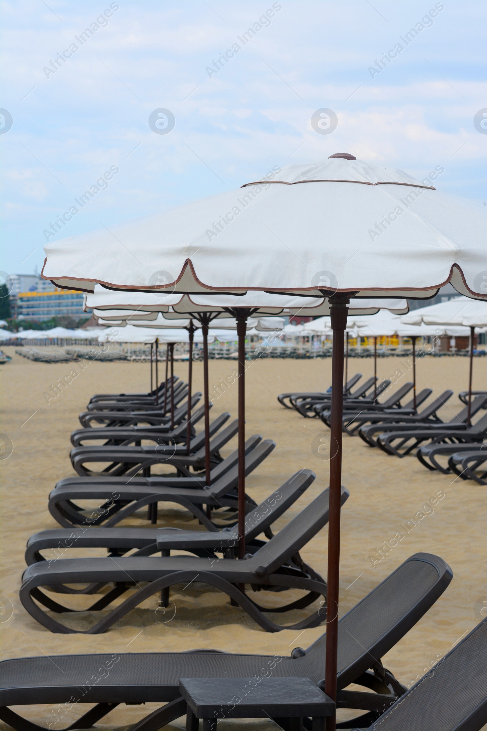 Photo of Many beautiful white umbrellas and black sunbeds on beach