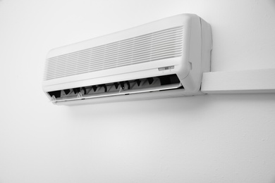 Photo of Modern air conditioner on white wall indoors