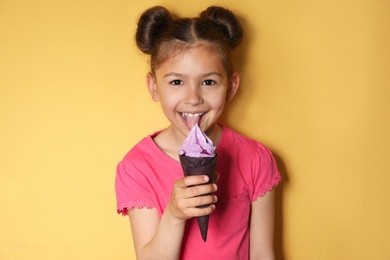 Photo of Adorable little girl with delicious ice cream against color background