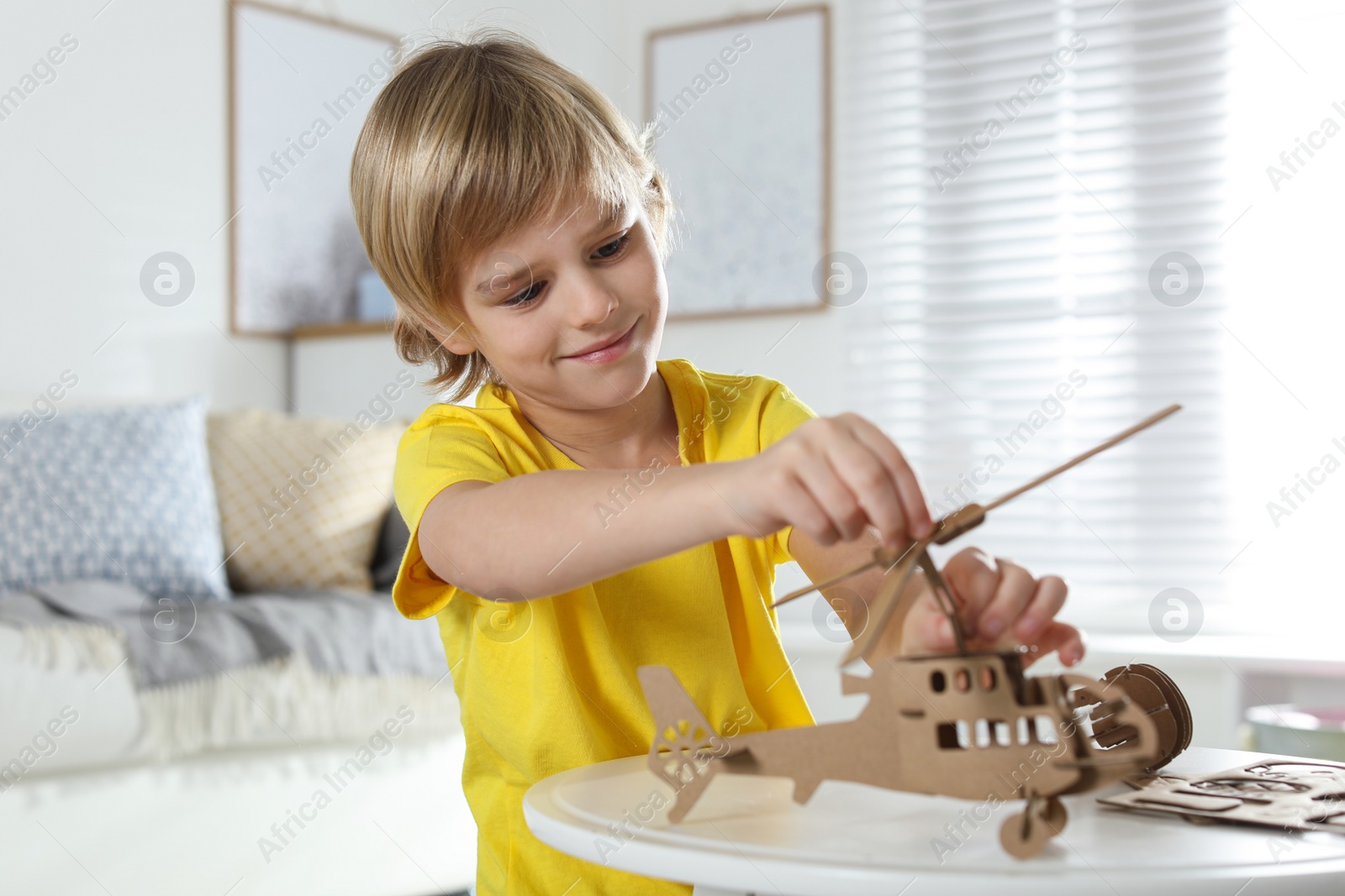 Photo of Little boy making carton toys at table indoors. Creative hobby