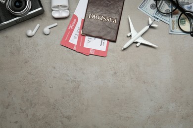 Flat lay composition with passport, toy plane and camera on grey table, space for text. Visa receiving