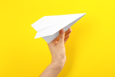 Photo of Woman holding paper plane on yellow background, closeup