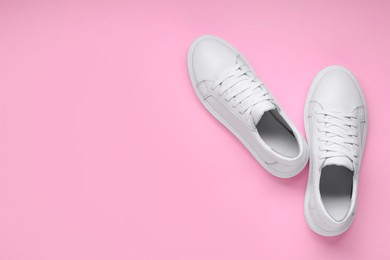 Photo of Pair of stylish white sneakers on pink background, top view. Space for text