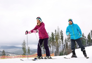 Photo of Couple of skiers on slope at resort. Winter vacation