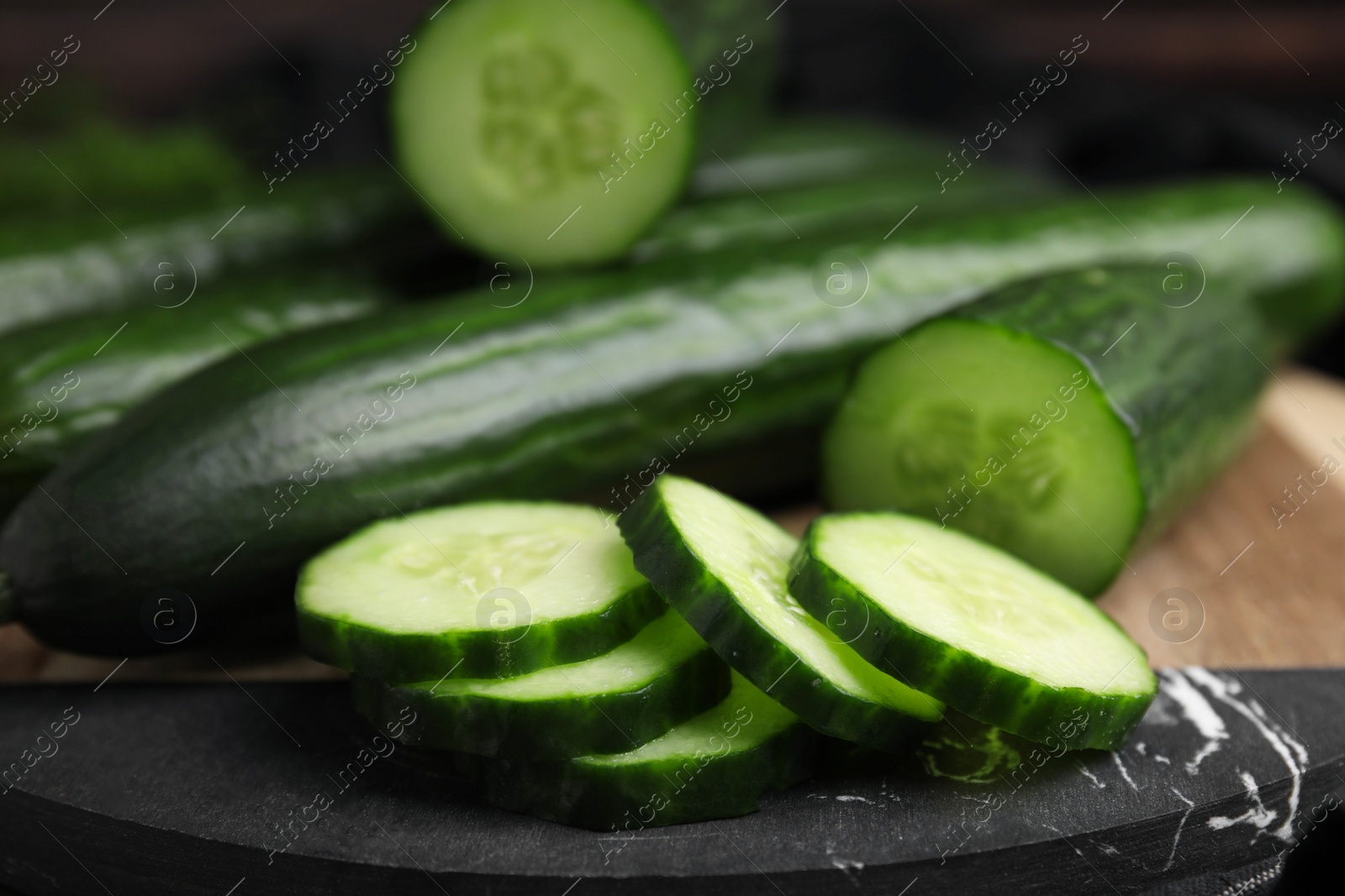 Photo of Fresh whole and cut cucumbers on board, closeup